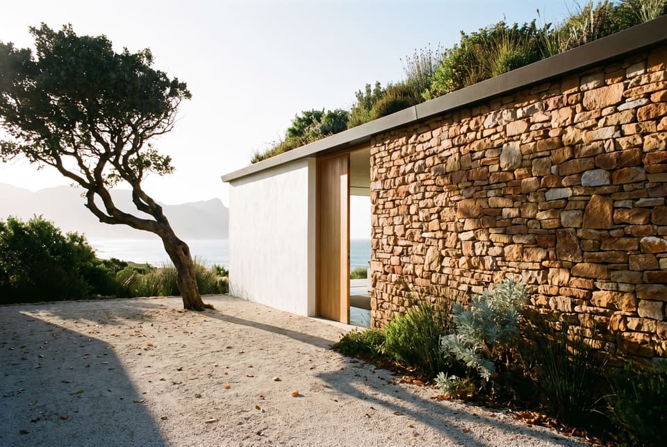 Arriving at the main house: a wind-bent milkwood, a gravel court, a rough sandstone wall and an oak door open to the sea